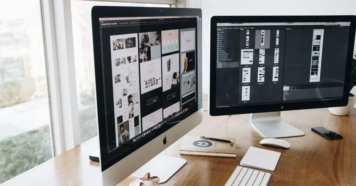 Un espace de travail numérique avec deux moniteurs, un clavier, une souris et des décorations sur un bureau en bois.